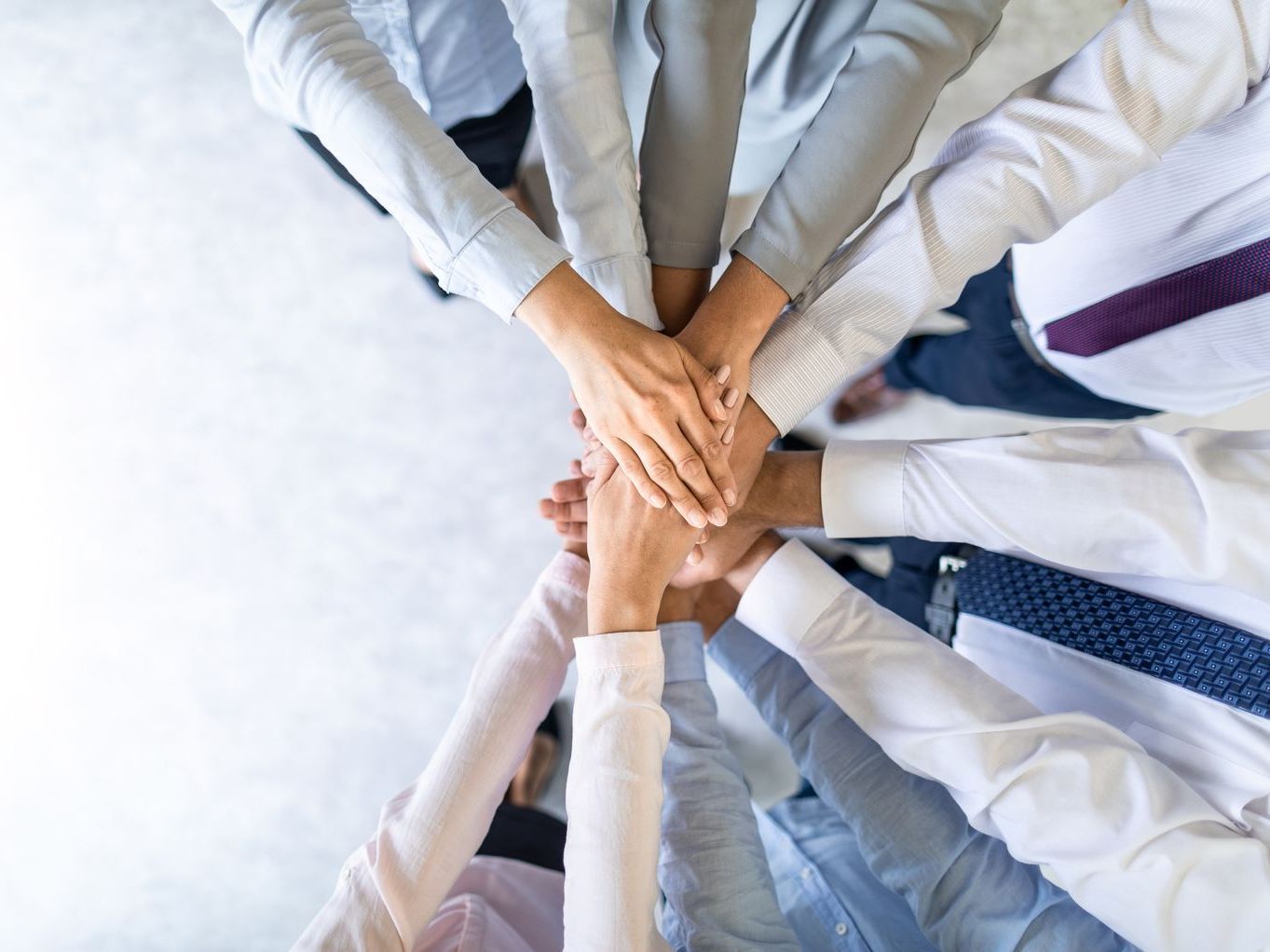 A group of people are putting their hands together in a circle.