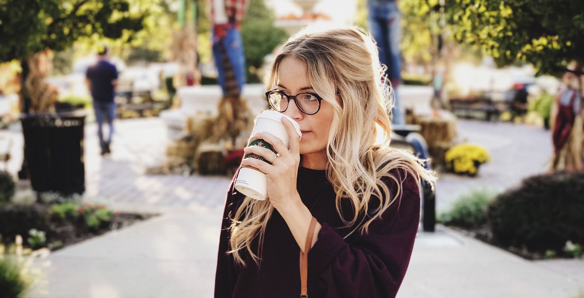 A woman is drinking a cup of coffee in a park.