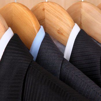 Suits with shirts on hangers on wooden background