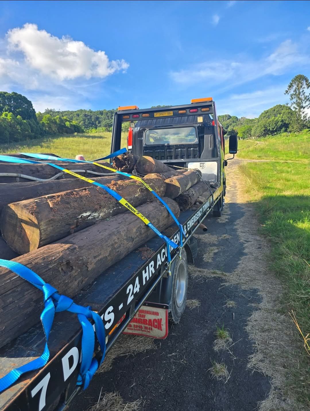 A Blue Car is Being Towed Down a Highway by a Tow Truck — Aura Towing Service in Baringa, QLD