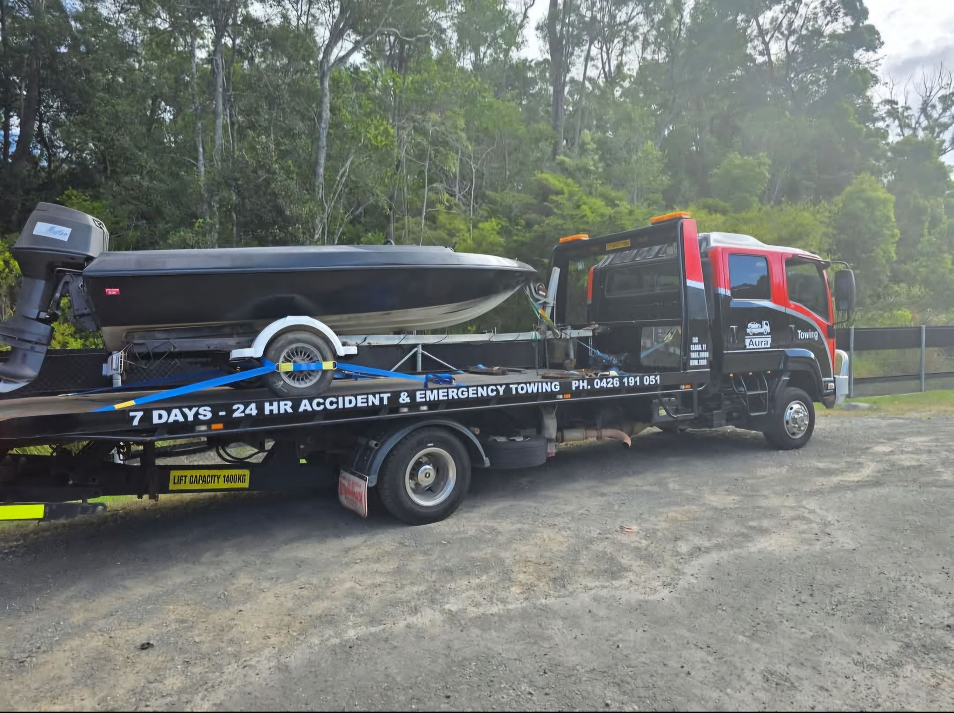A tow truck is carrying a boat on a trailer. — Aura Towing Service in Caloundra, QLD
