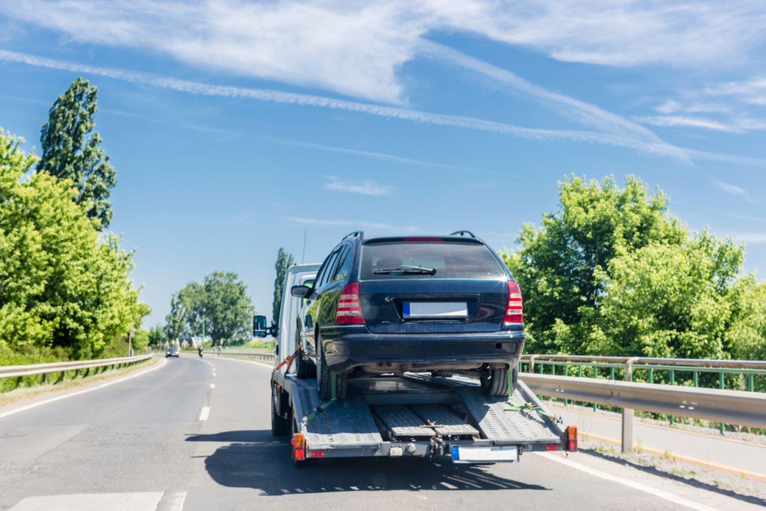 A Car is Being Towed Down a Highway by a Tow Truck — Aura Towing Service in Baringa, QLD