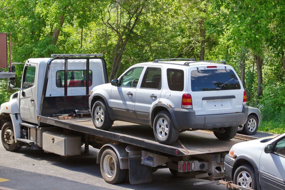 A White Car is Being Towed by a Tow Truck — Aura Towing Service in Caloundra, QLD