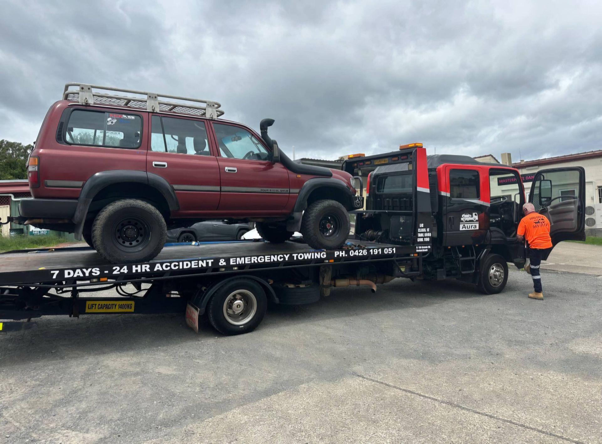 A White Car is Being Towed by a Tow Truck on a Highway — Aura Towing Service in Baringa, QLD