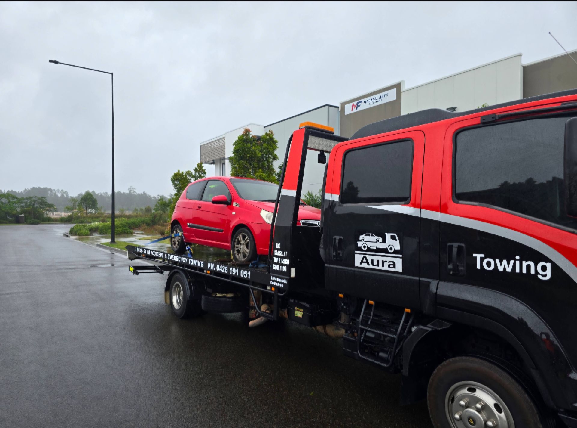 A red car is being towed by a towing truck — Aura Towing Service in Caloundra, QLD