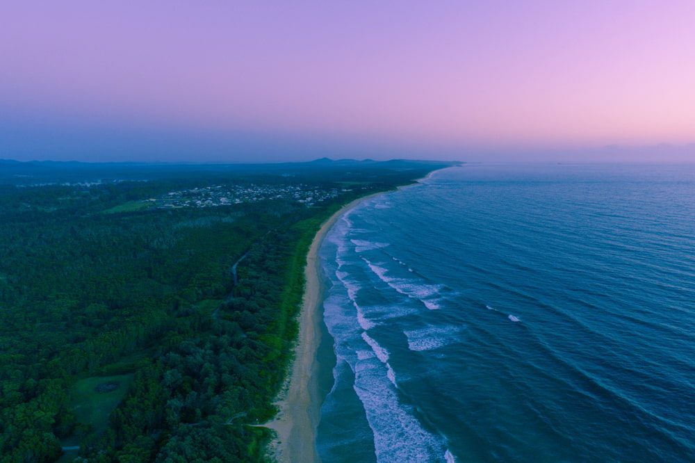 Sandy Beach, Ocean Waves, Dark Green Treeline — Aura Towing Service in Nirimba, QLD