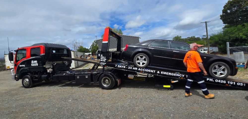 A Black Tow Truck With a Black Car on Its Platform — Aura Towing Service in Nirimba, QLD