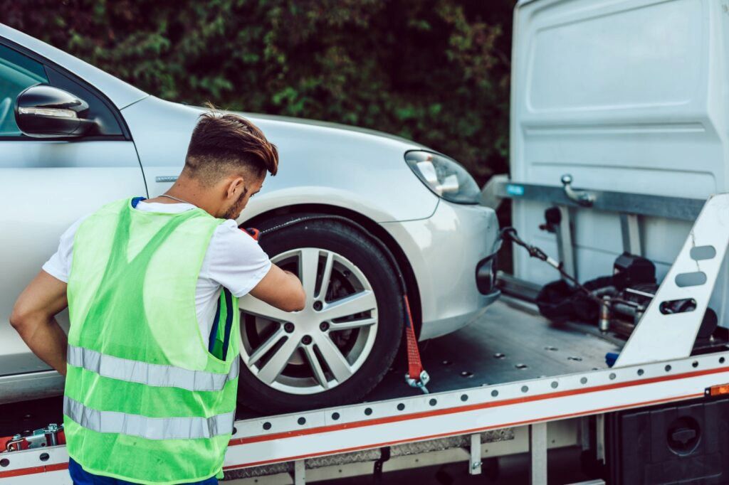 Tow Truck Operator Securing a Silver Car Onto a Flatbed Truck — Aura Towing Service in Banya, QLD