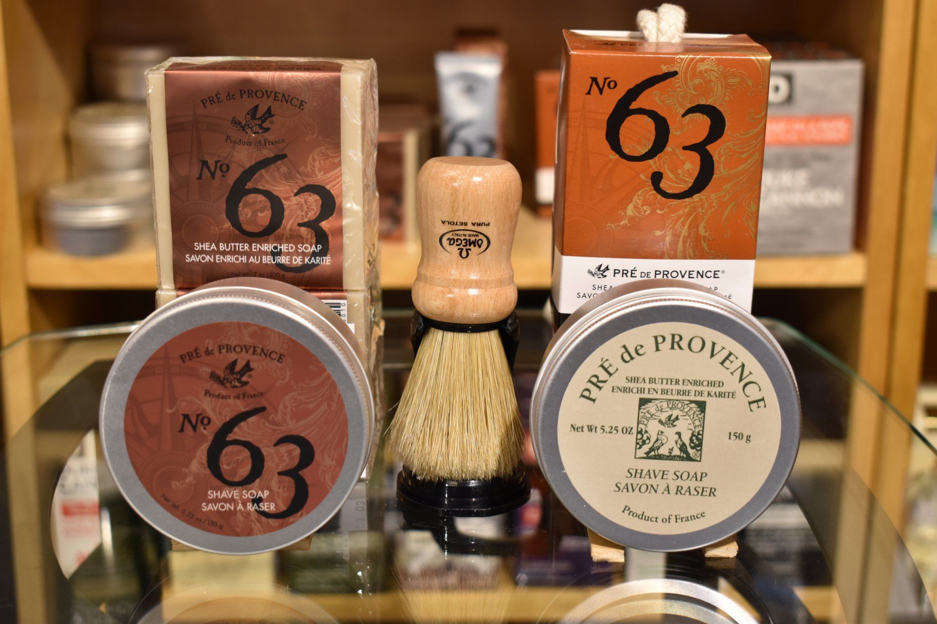 A shaving brush is sitting on a glass table next to a shaving cream.