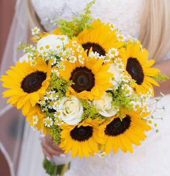 A bride is holding a bouquet of sunflowers and white roses