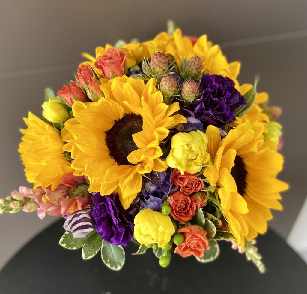 A bouquet of sunflowers and purple flowers on a table