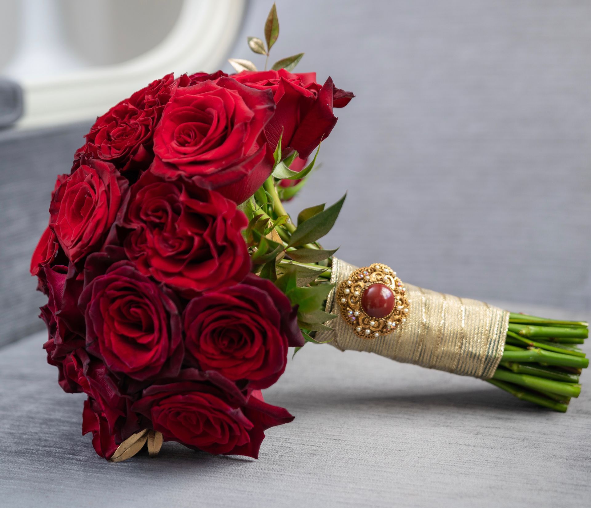 A bouquet of red roses with a brooch on it