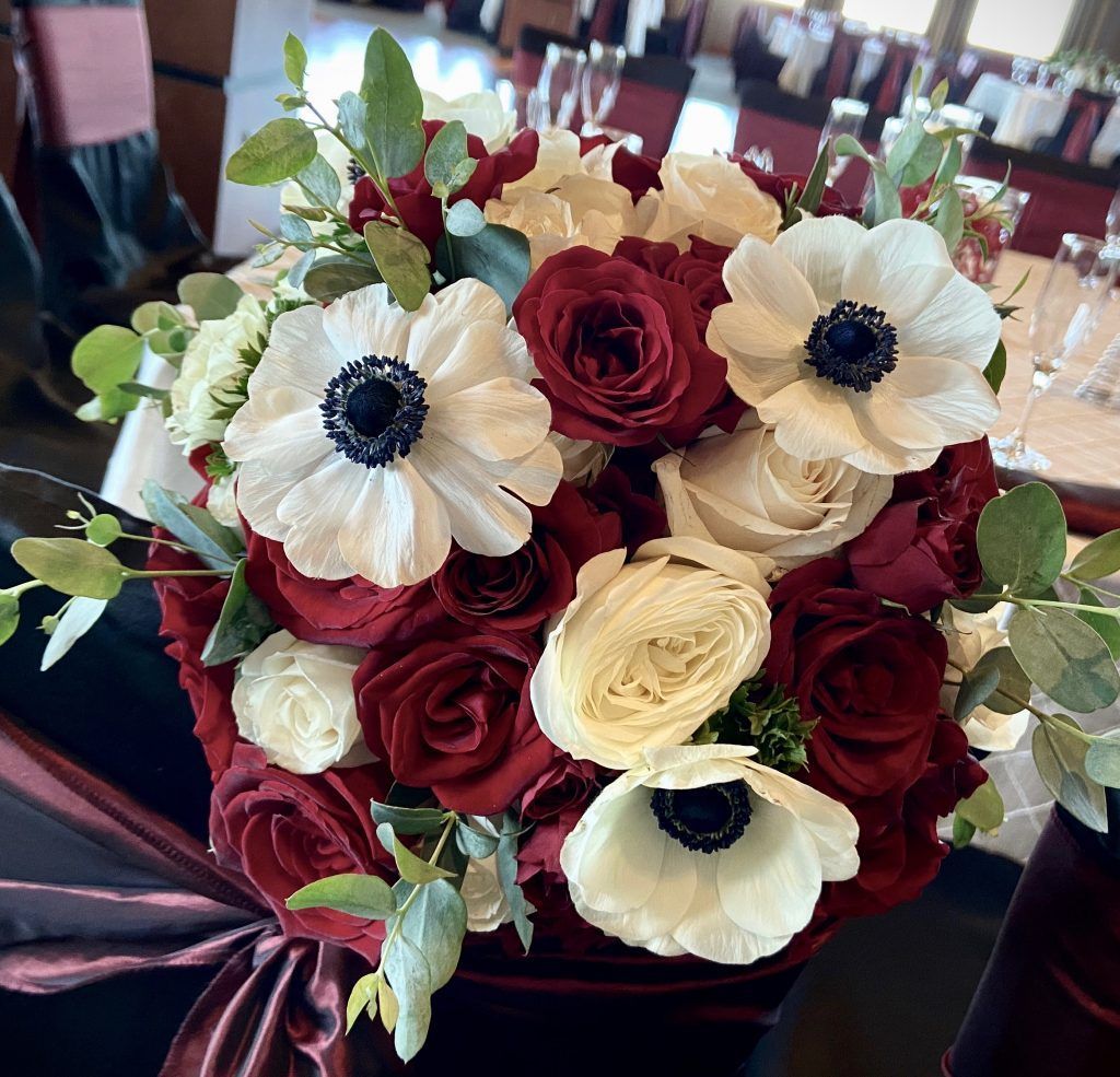 A bouquet of red roses and white anemones on a table