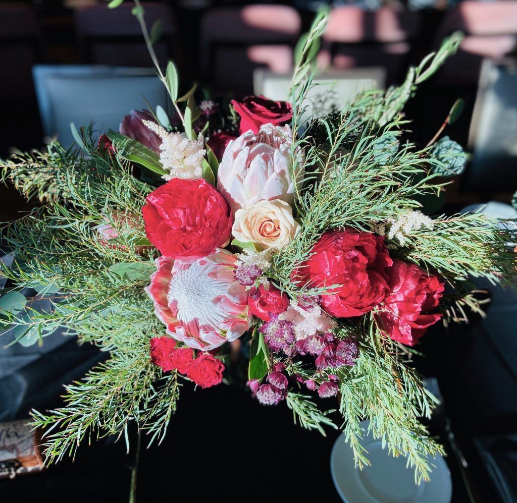 A bouquet of red and white flowers and greenery on a table