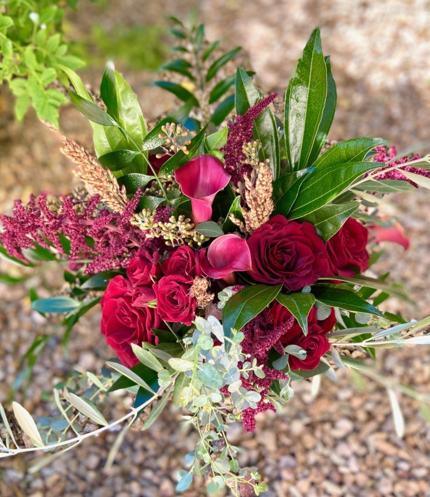 A bouquet of red flowers and greenery is sitting on the ground.