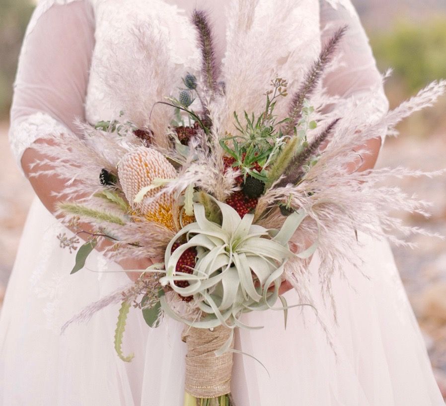 A bride in a white dress is holding a bouquet of flowers.