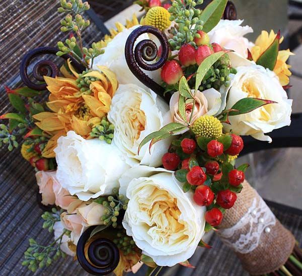 A bouquet of yellow and white flowers with red berries