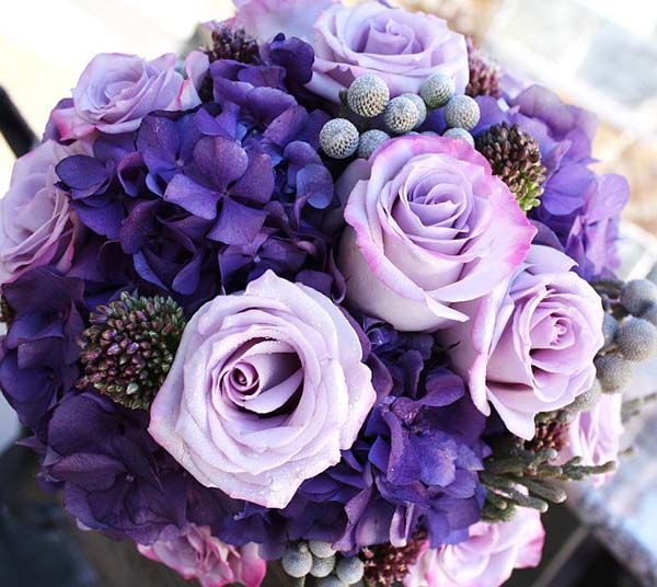 A bouquet of purple flowers including roses and hydrangea