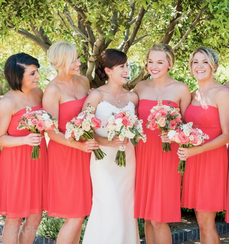 A bride and her bridesmaids are posing for a picture while holding bouquets of flowers.