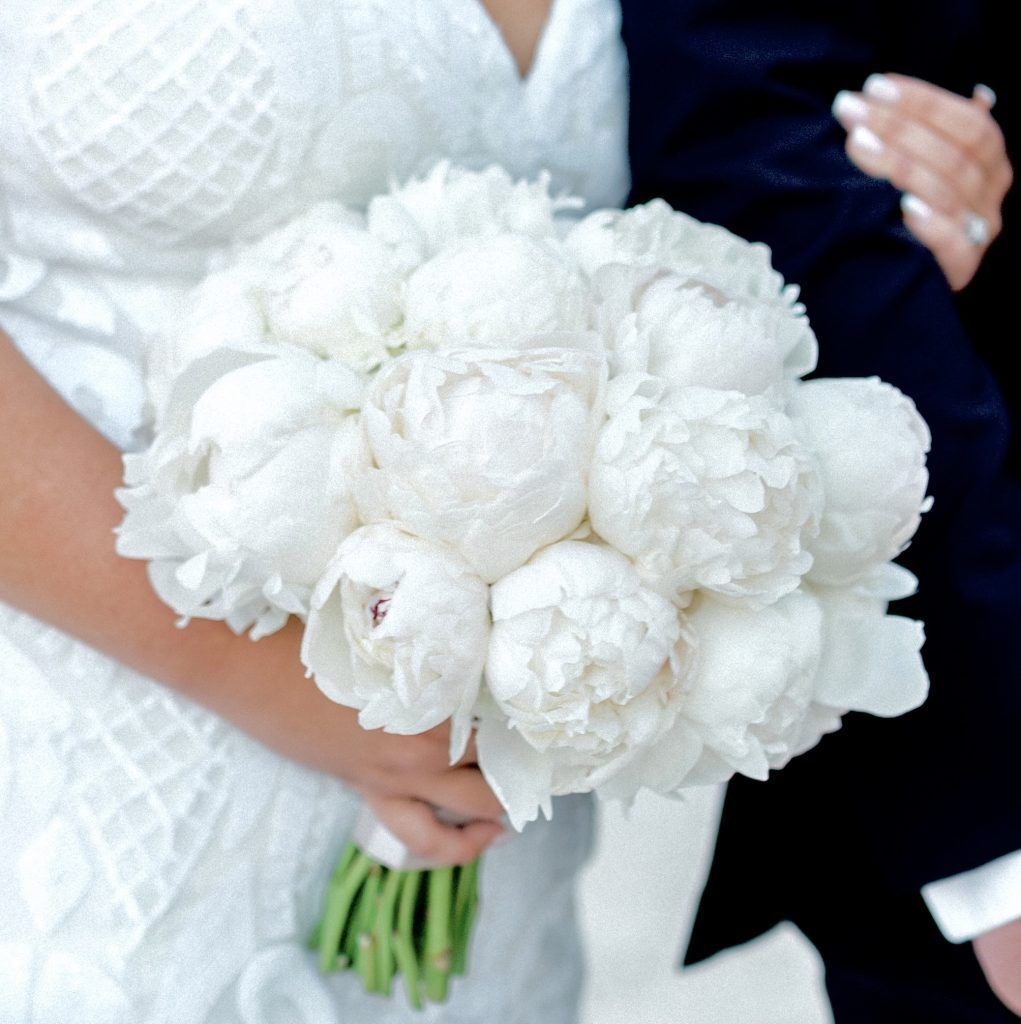 A bride is holding a bouquet of white flowers