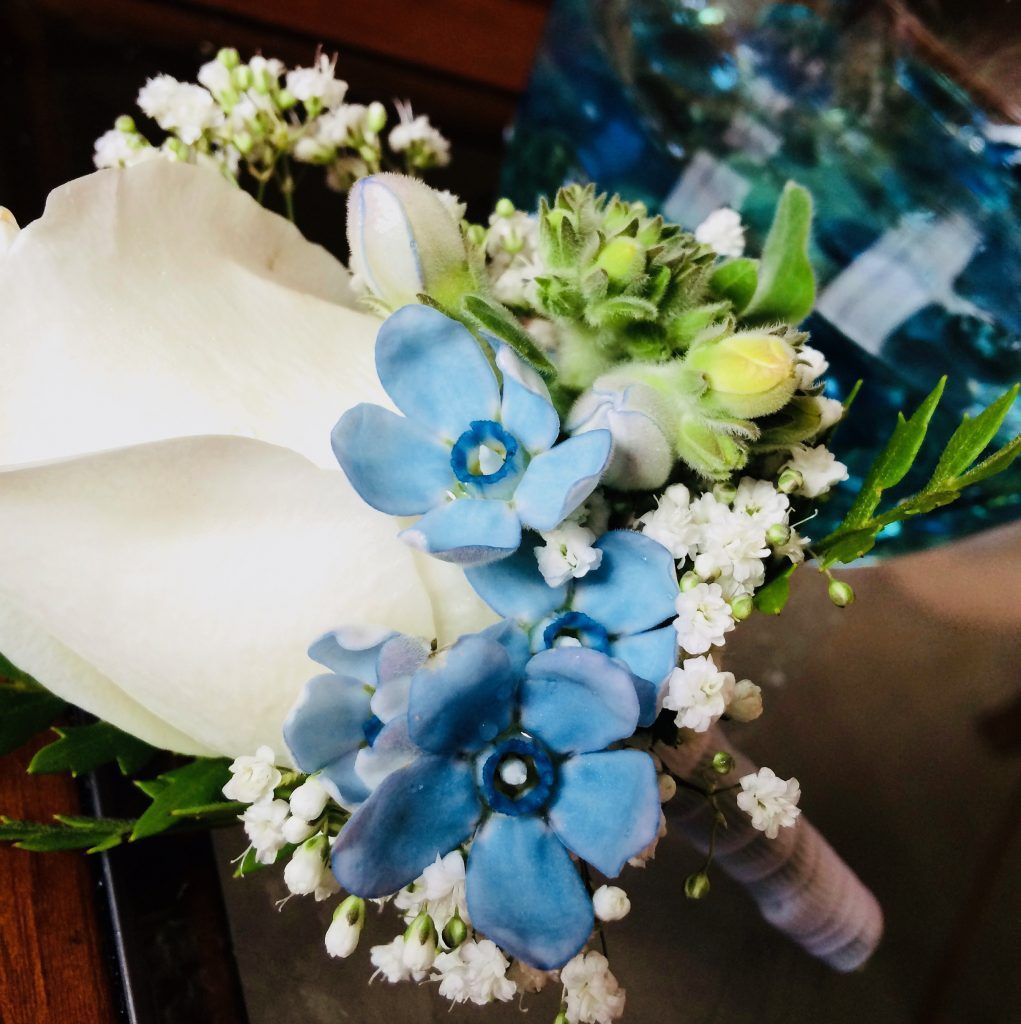A white rose with blue flowers and baby 's breath