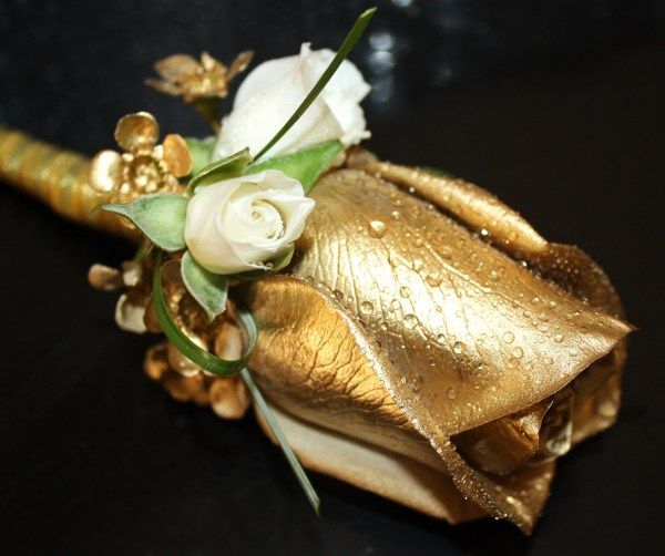 A gold rose with white flowers on a black background