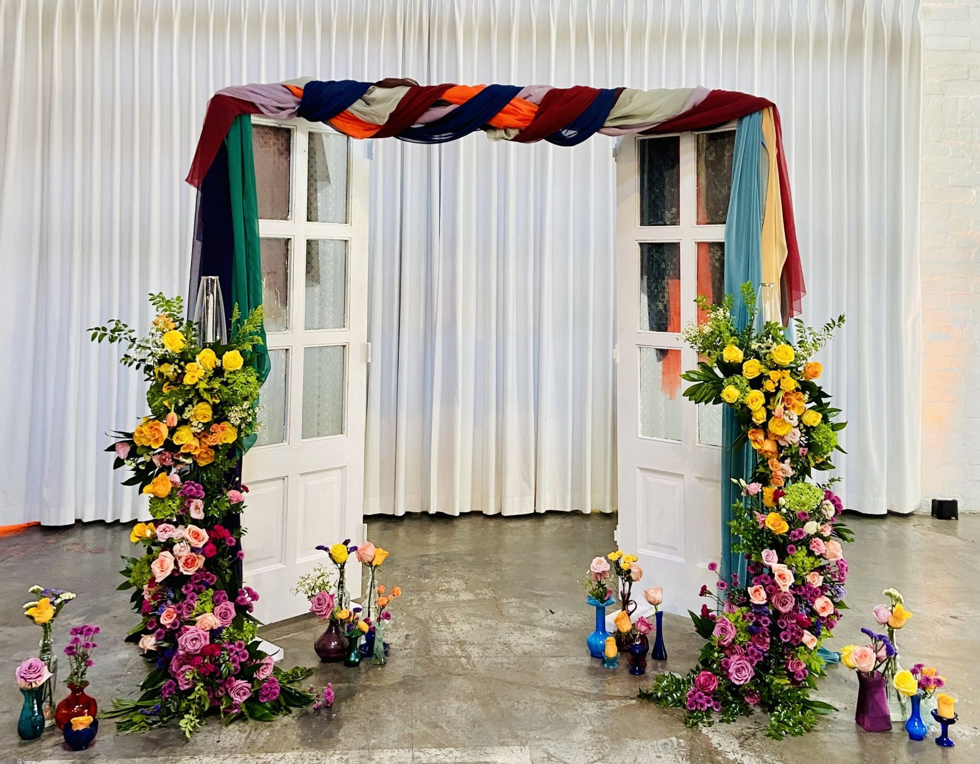 A wedding arch decorated with flowers and doors in a room.