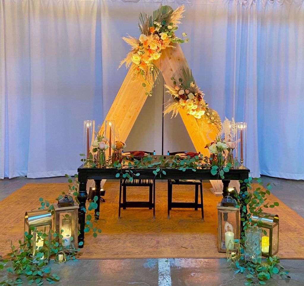 A table with candles and flowers on it in front of a tent.