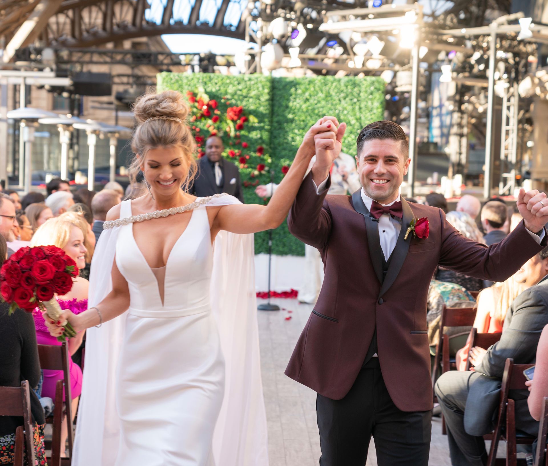 A bride and groom are walking down the aisle holding hands.