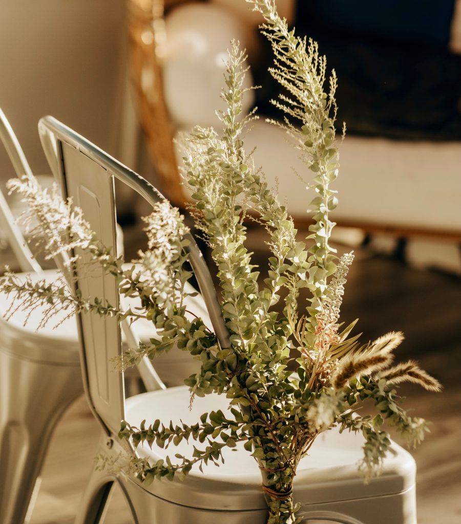 A vase of flowers is sitting on a chair.