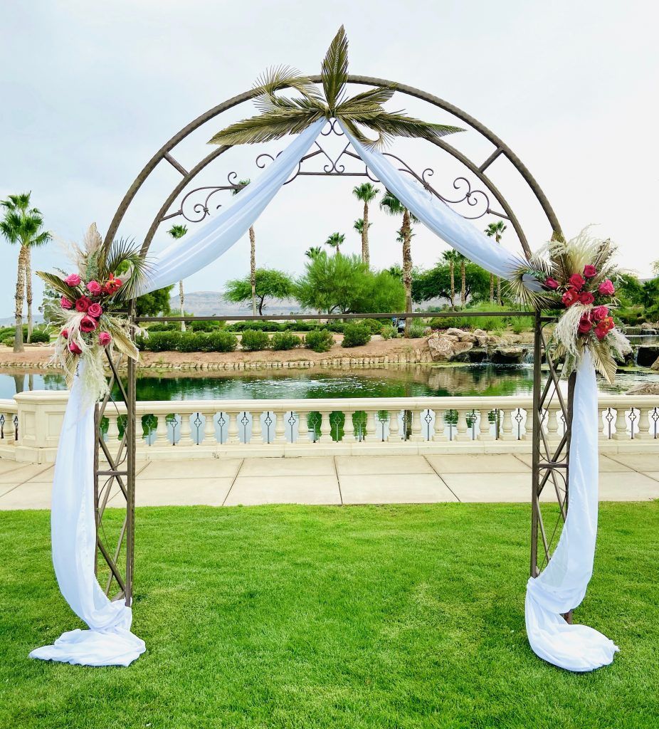 A wedding arch is sitting on top of a lush green field.
