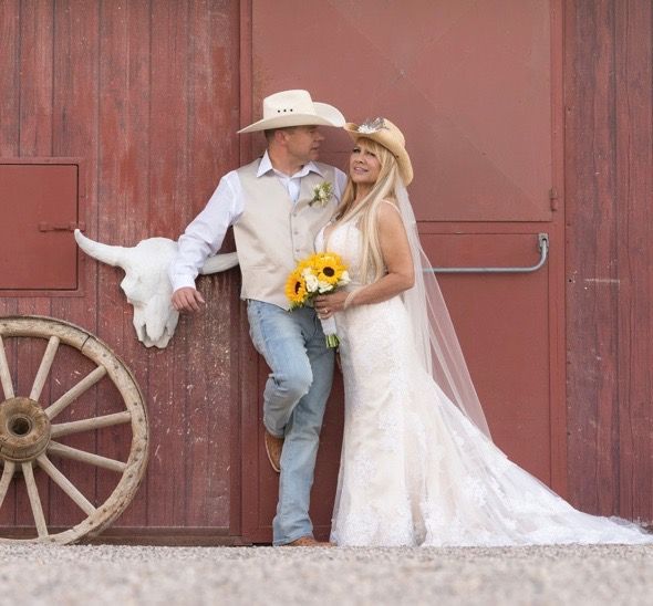 A bride and groom pose in front of a red barn
