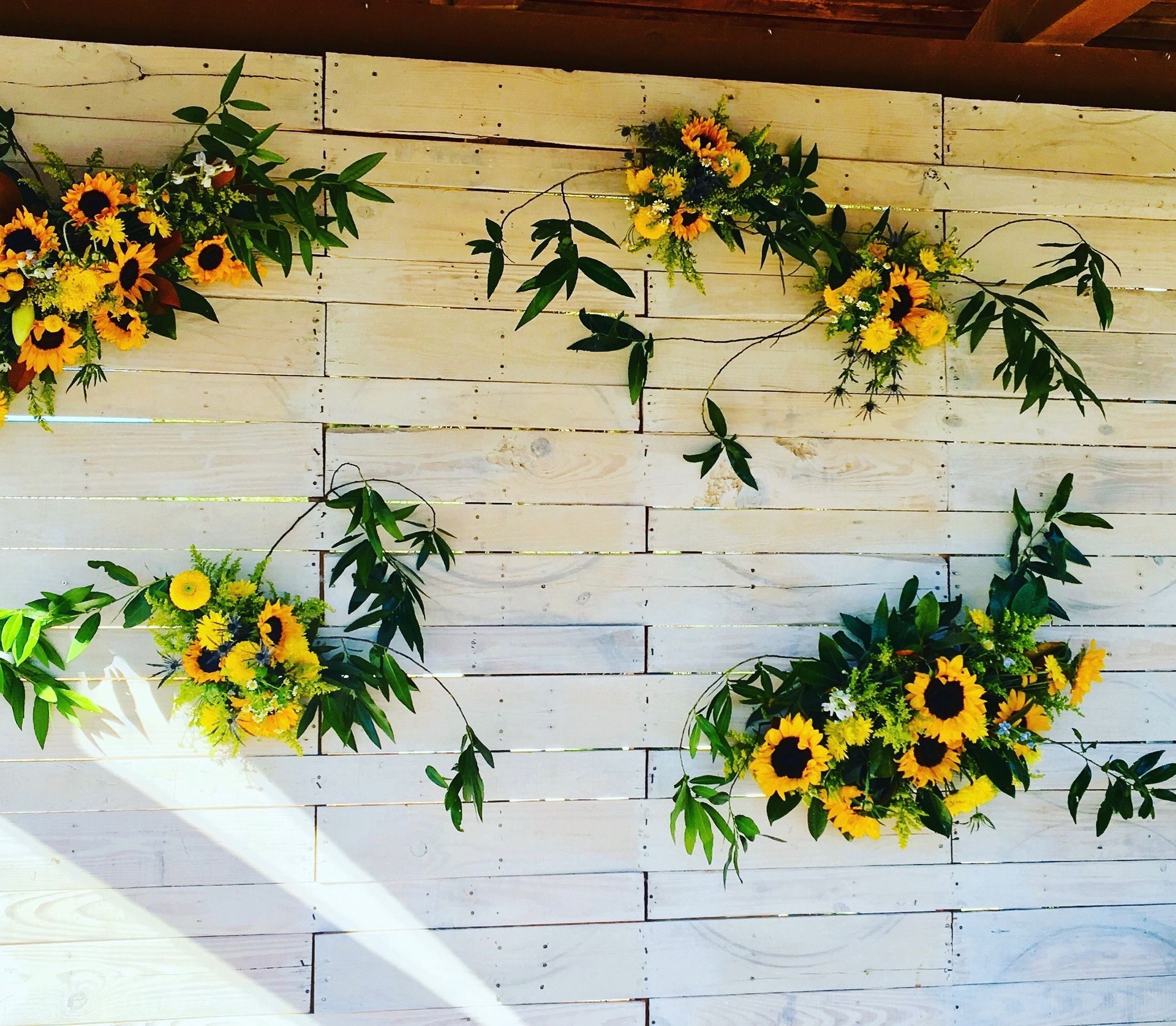 A white wooden wall with yellow flowers and green leaves
