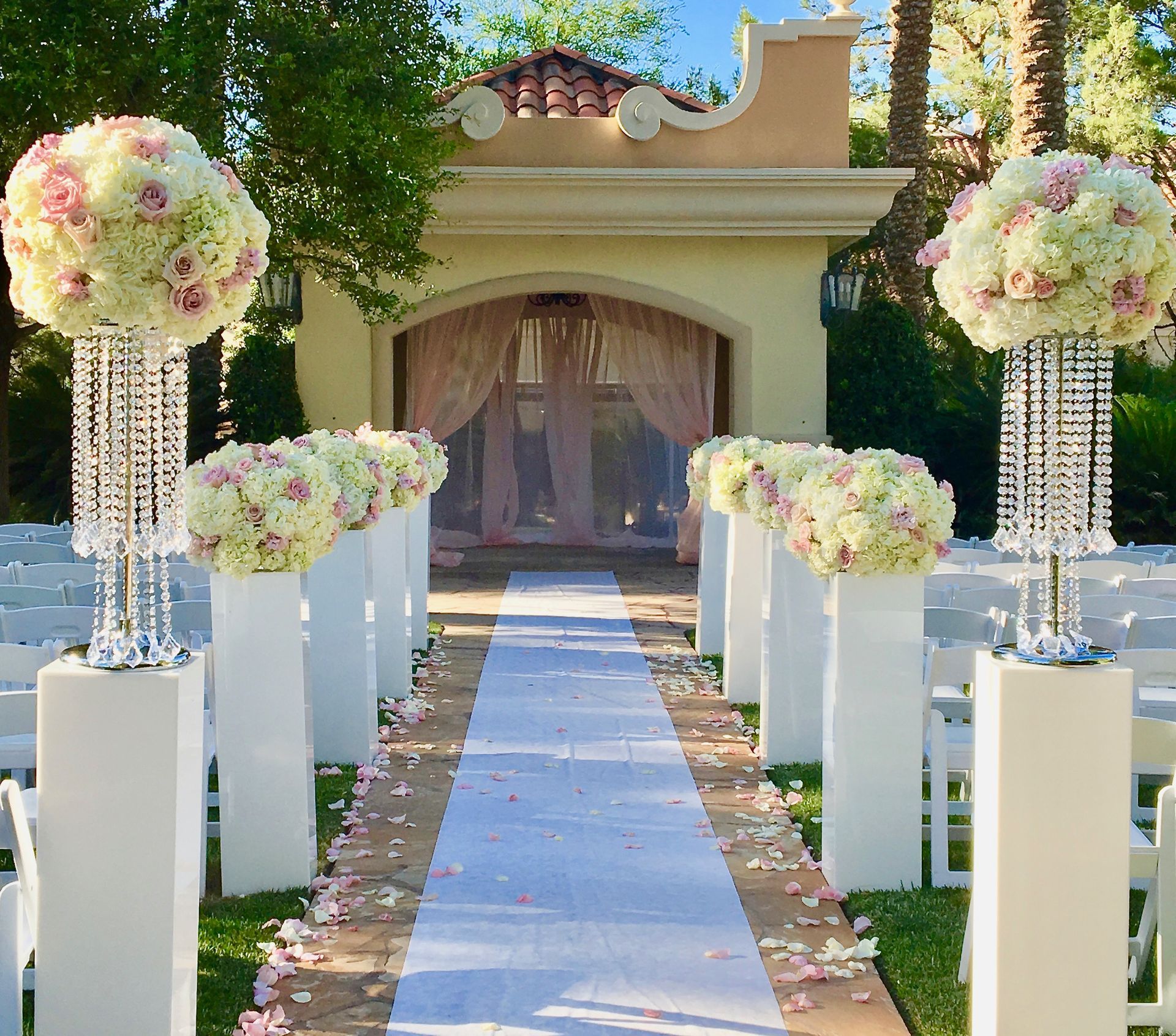 A wedding aisle is decorated with flowers and crystals