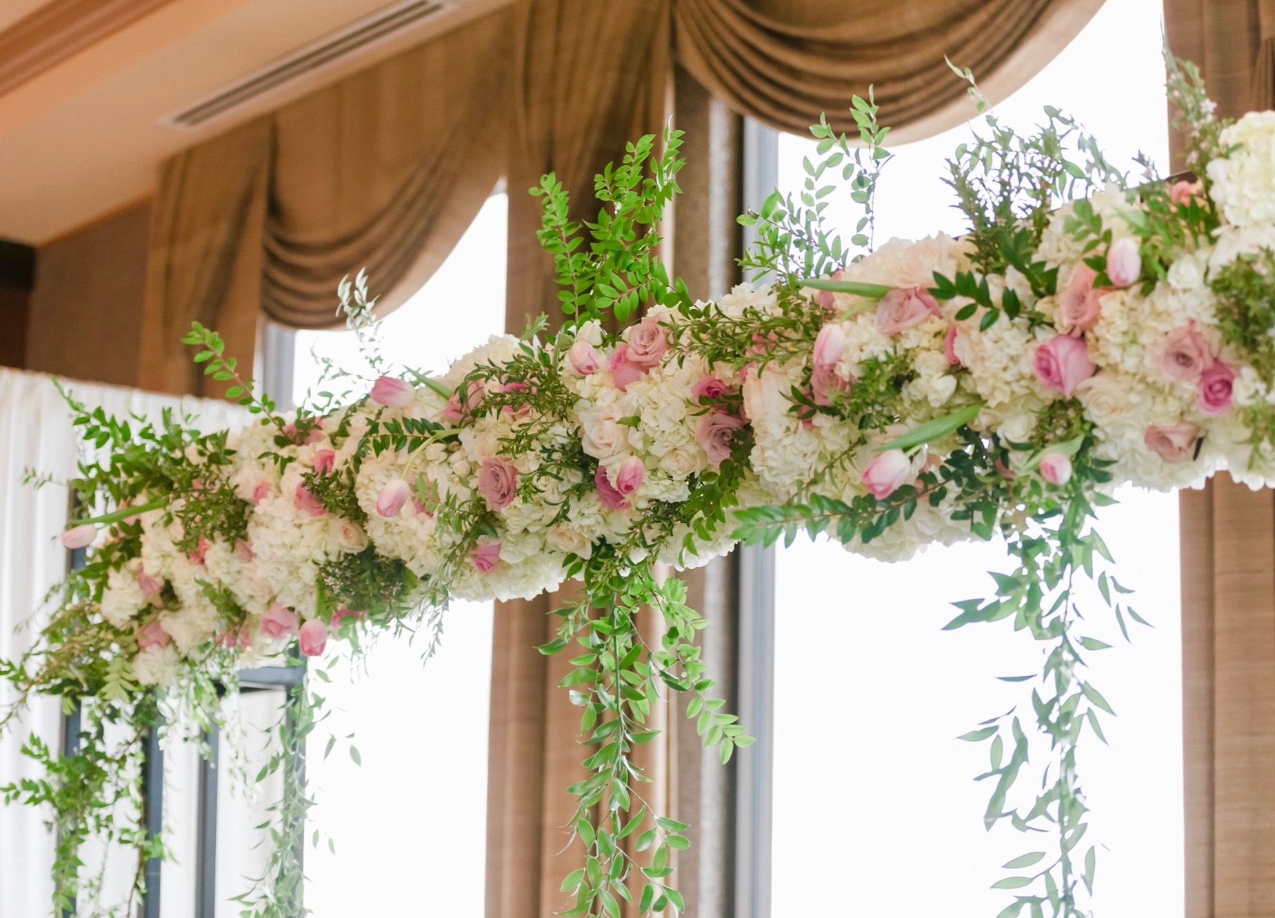 A wedding arch decorated with pink and white flowers and greenery.