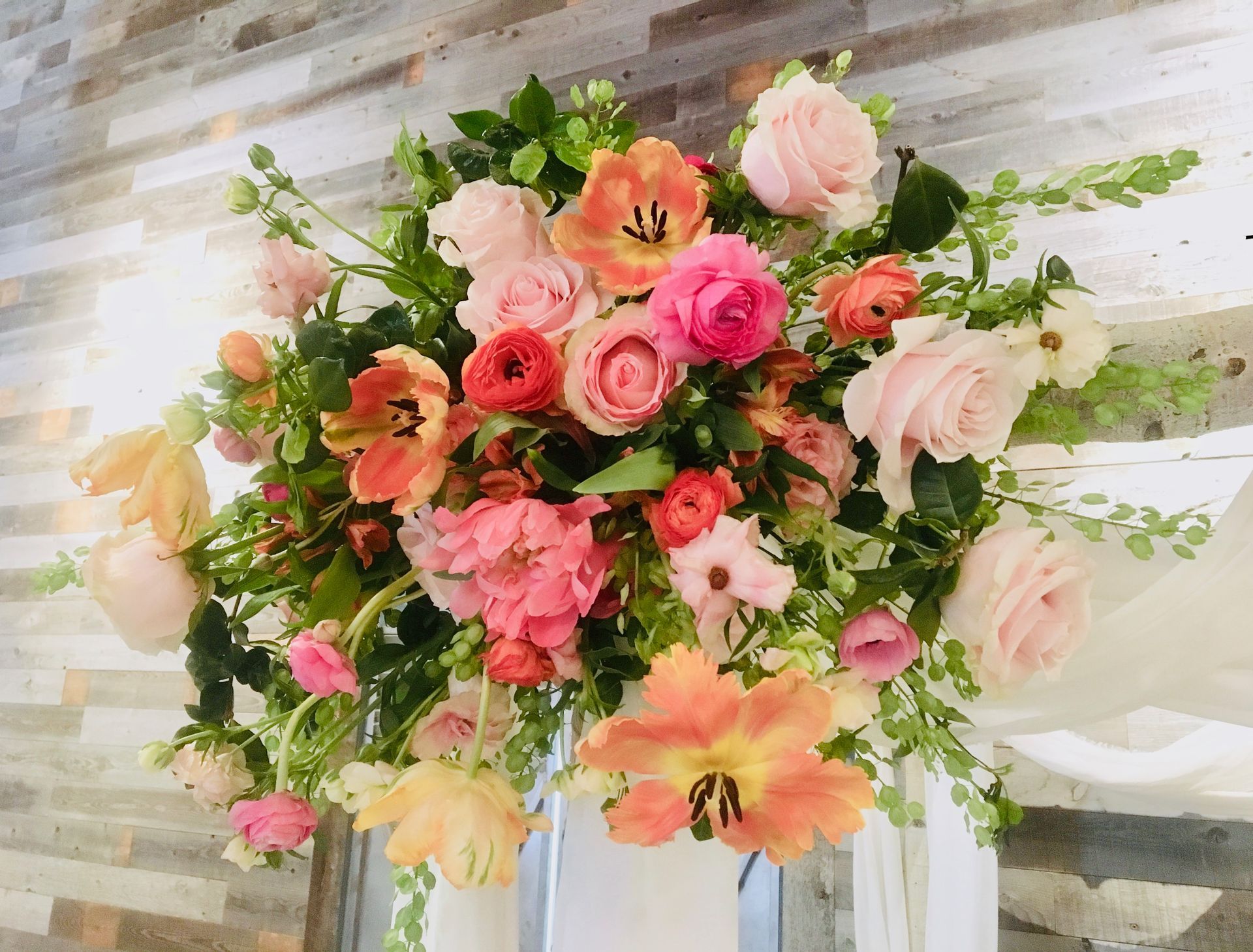 A bunch of flowers are sitting on a table in front of a wooden wall.