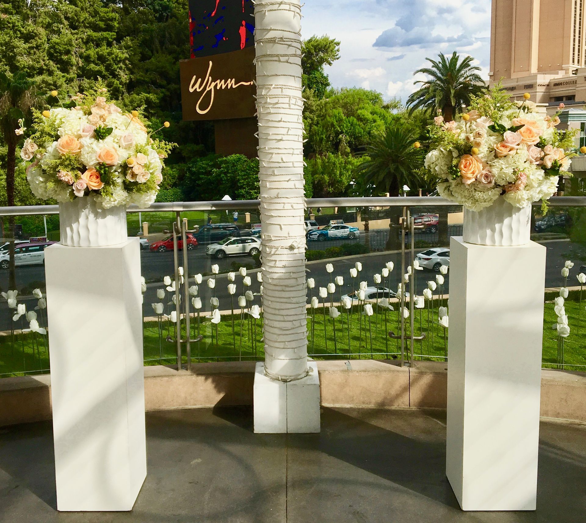 Two white columns with flowers in front of a sign that says wynn