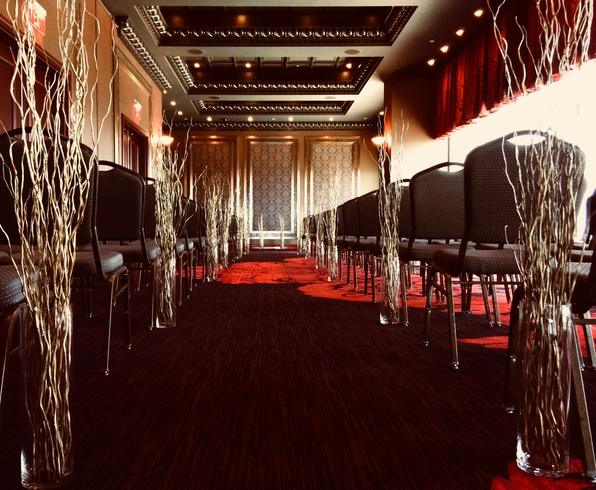 A long hallway with rows of chairs and vases