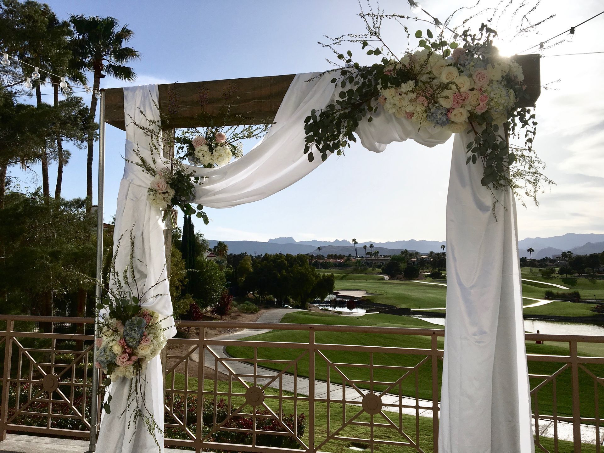 A wedding arch decorated with white flowers and a view of a golf course