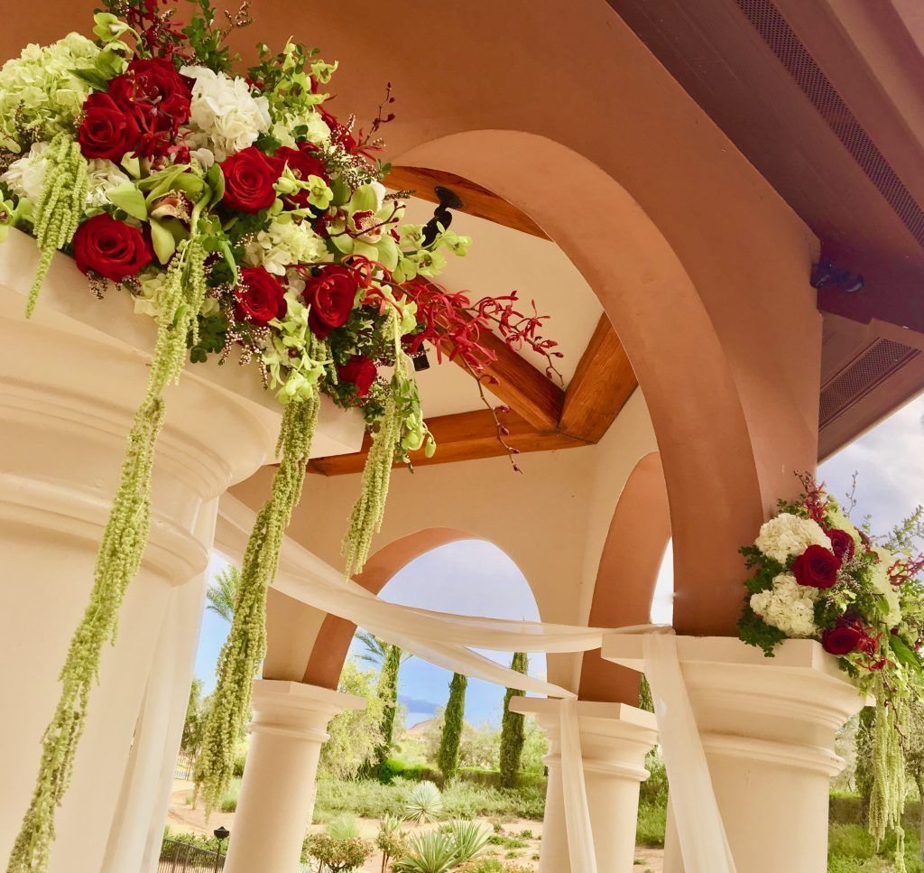 A gazebo is decorated with red and white flowers