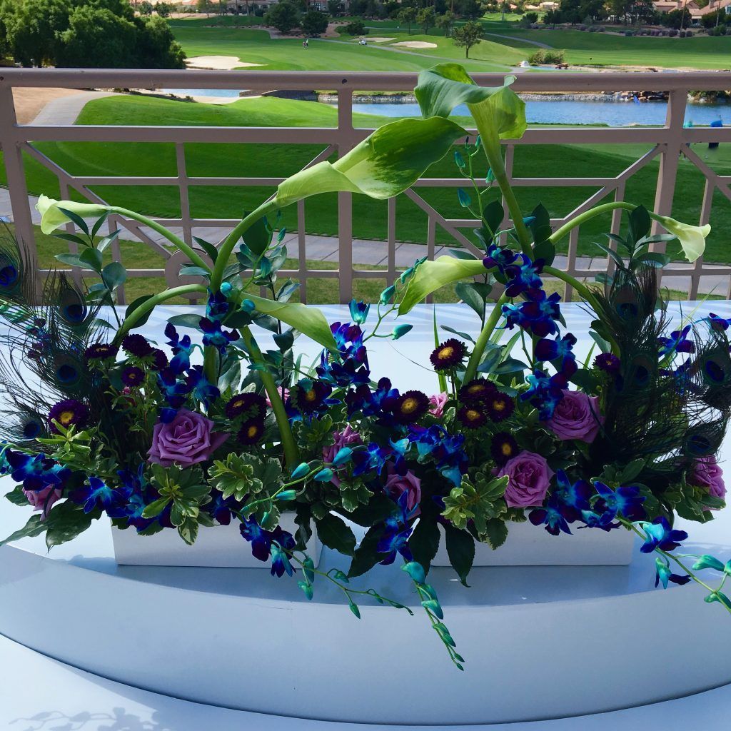 A display of blue and purple flowers with peacock feathers