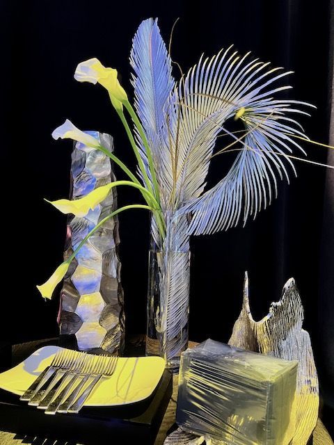 A table with a vase of feathers and flowers on it