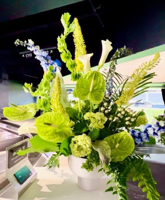 A white vase filled with green and white flowers