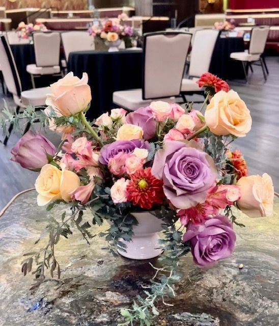 A vase filled with pink and purple flowers is on a table.