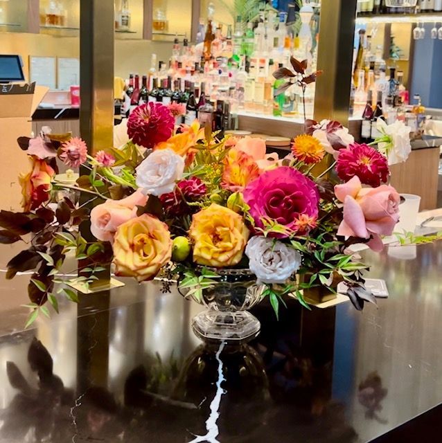 A vase of flowers sits on a counter in a restaurant