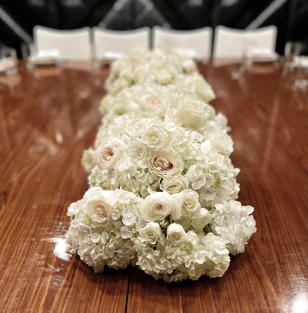 A long row of white flowers on a wooden table