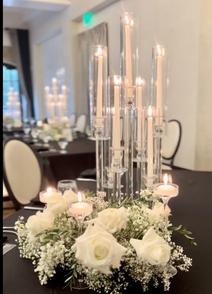 A table with a vase of flowers and candles on it.
