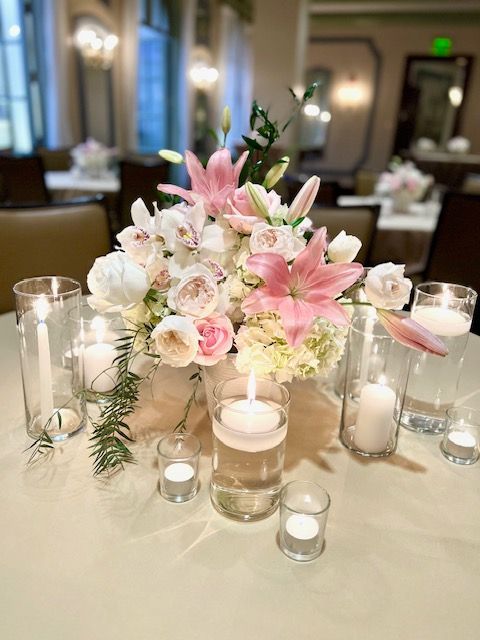 A table with a vase of flowers and candles on it.