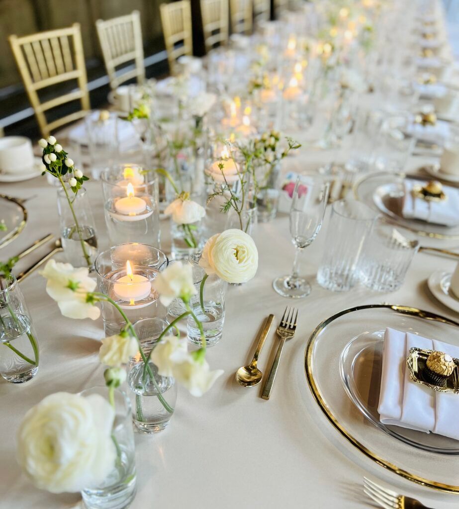 A long table with plates , utensils , candles and flowers on it.