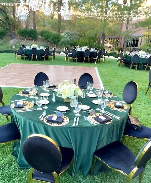 A round table with a green table cloth and black chairs